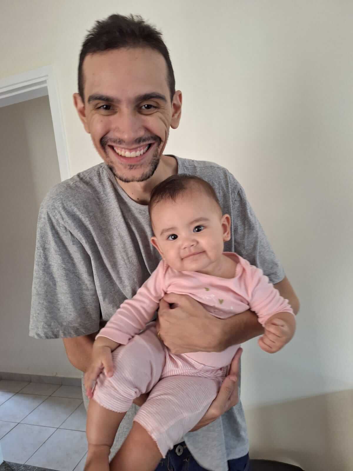Denis segurando sua filha Carol, simbolizando equilíbrio entre carreira em engenharia de dados e vida pessoal.
